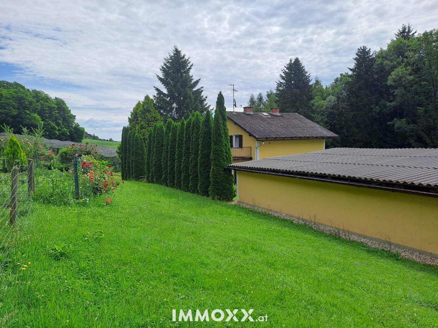 Großzügiger Gartenbereich mit hohen Hecken und dem Haus im Hintergrund, umgeben von viel Grün.