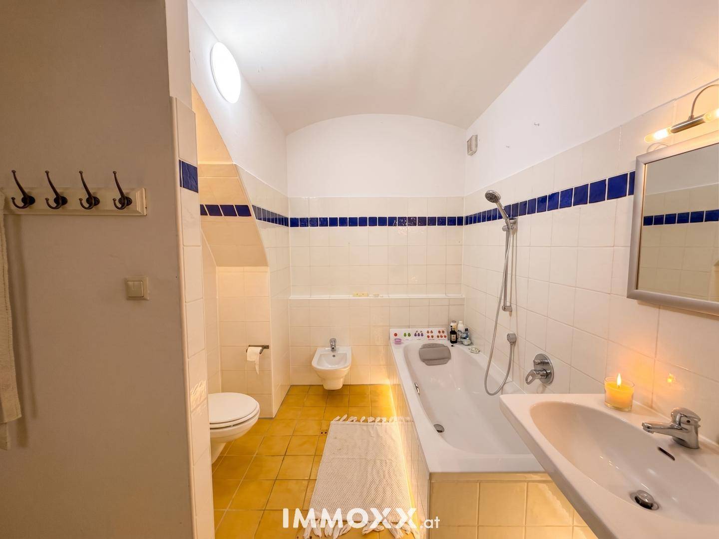 Helles Badezimmer mit Badewanne, Toilette, Bidet und Waschbecken, unter einem Oberlicht.