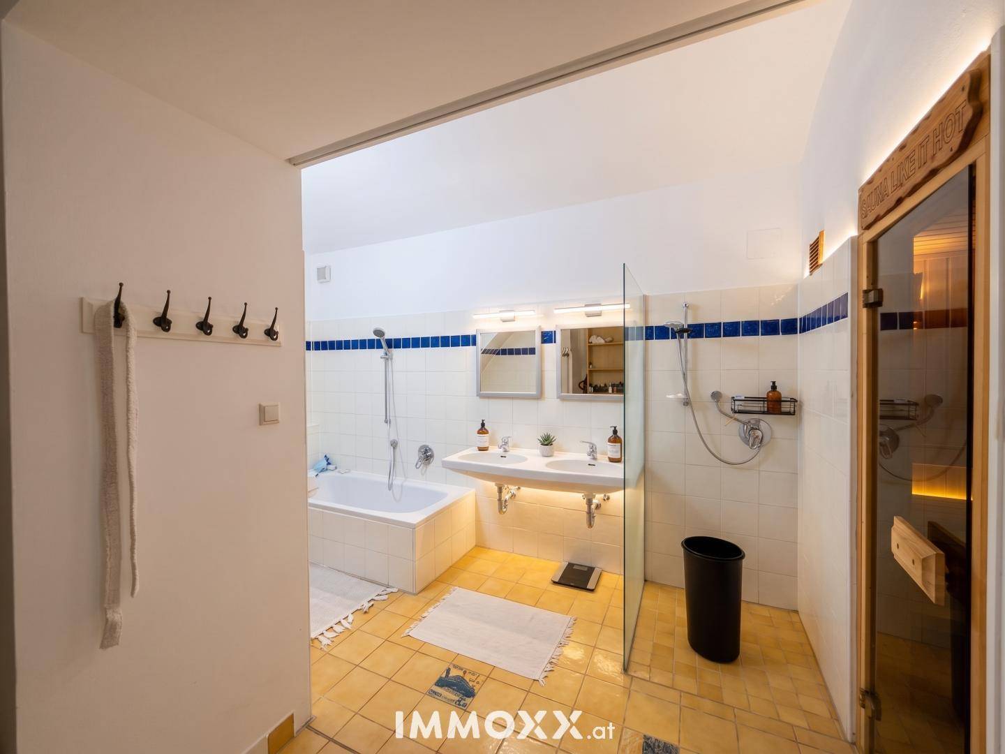 Geräumiges Badezimmer mit Badewanne, Doppelwaschbecken und integrierter Sauna für Wellness.