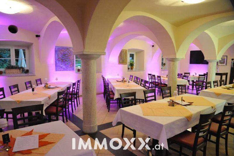 Großer Speisesaal mit Gewölbedecken, Säulen und festlich gedeckten Tischen, beleuchtet mit violettem Licht.