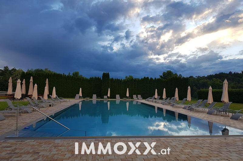 Der große Außenpoolbereich bei Sonnenuntergang, umgeben von Liegestühlen und Sonnenschirmen.