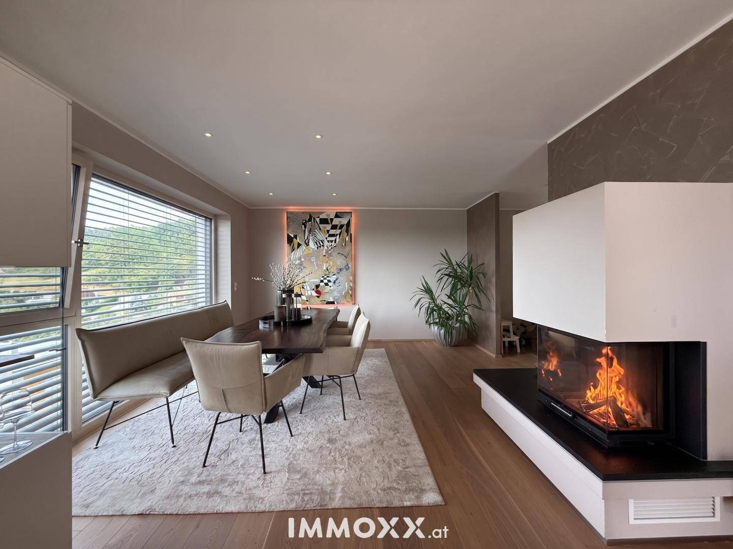 Gemütlicher Essbereich mit modernem Kamin, Holzboden und großem Fenster für viel Licht.