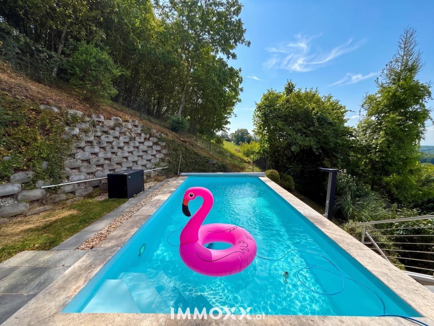 Erfrischender Swimmingpool mit einem pinken Flamingo-Schwimmtier, umgeben von Natur.