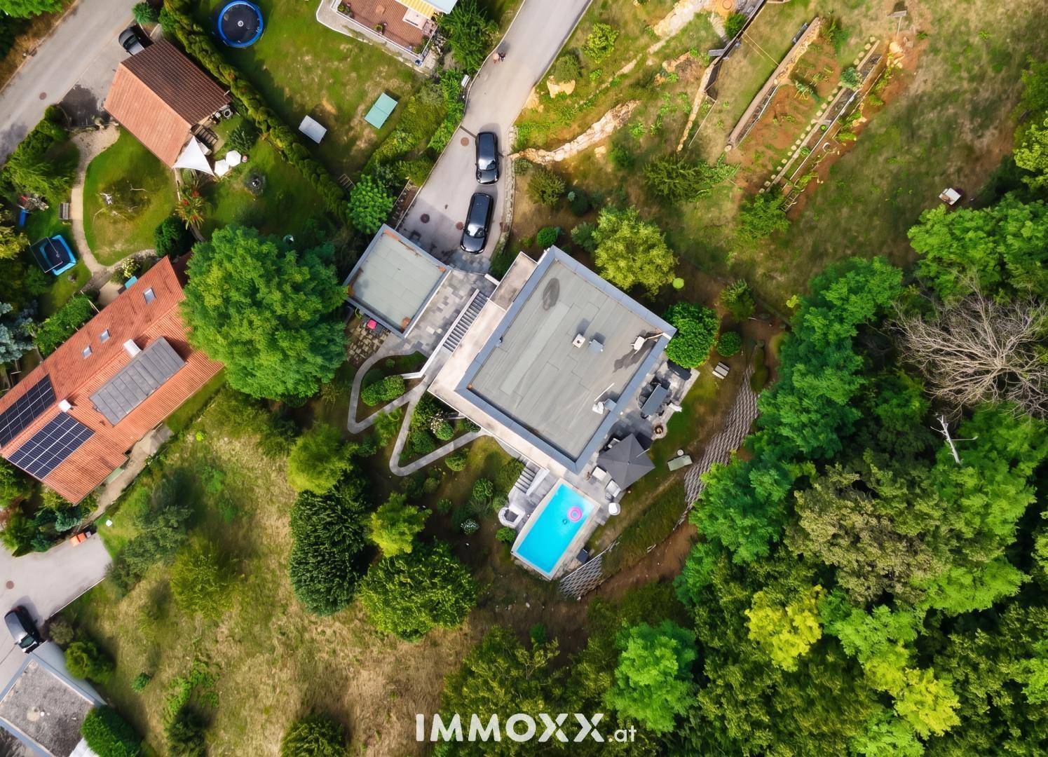 Weitläufige Luftaufnahme der modernen Villa mit Pool und der umliegenden grünen Landschaft.