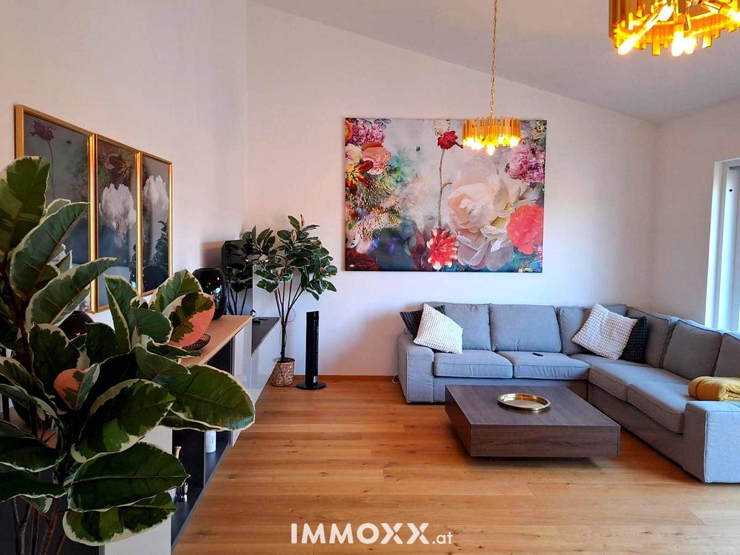 Helles Wohnzimmer mit modernem Sofa, Holzboden und farbenfroher Kunst an der Wand.