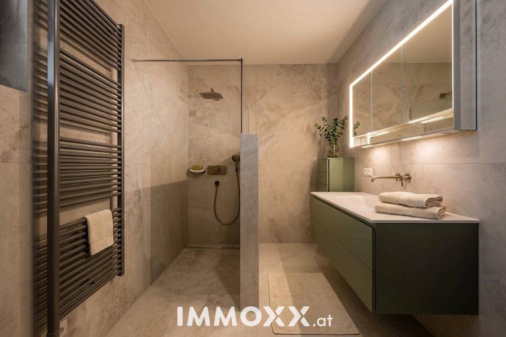 Modernes Badezimmer mit begehbarer Dusche, beheiztem Handtuchhalter und beleuchtetem Spiegelschrank.