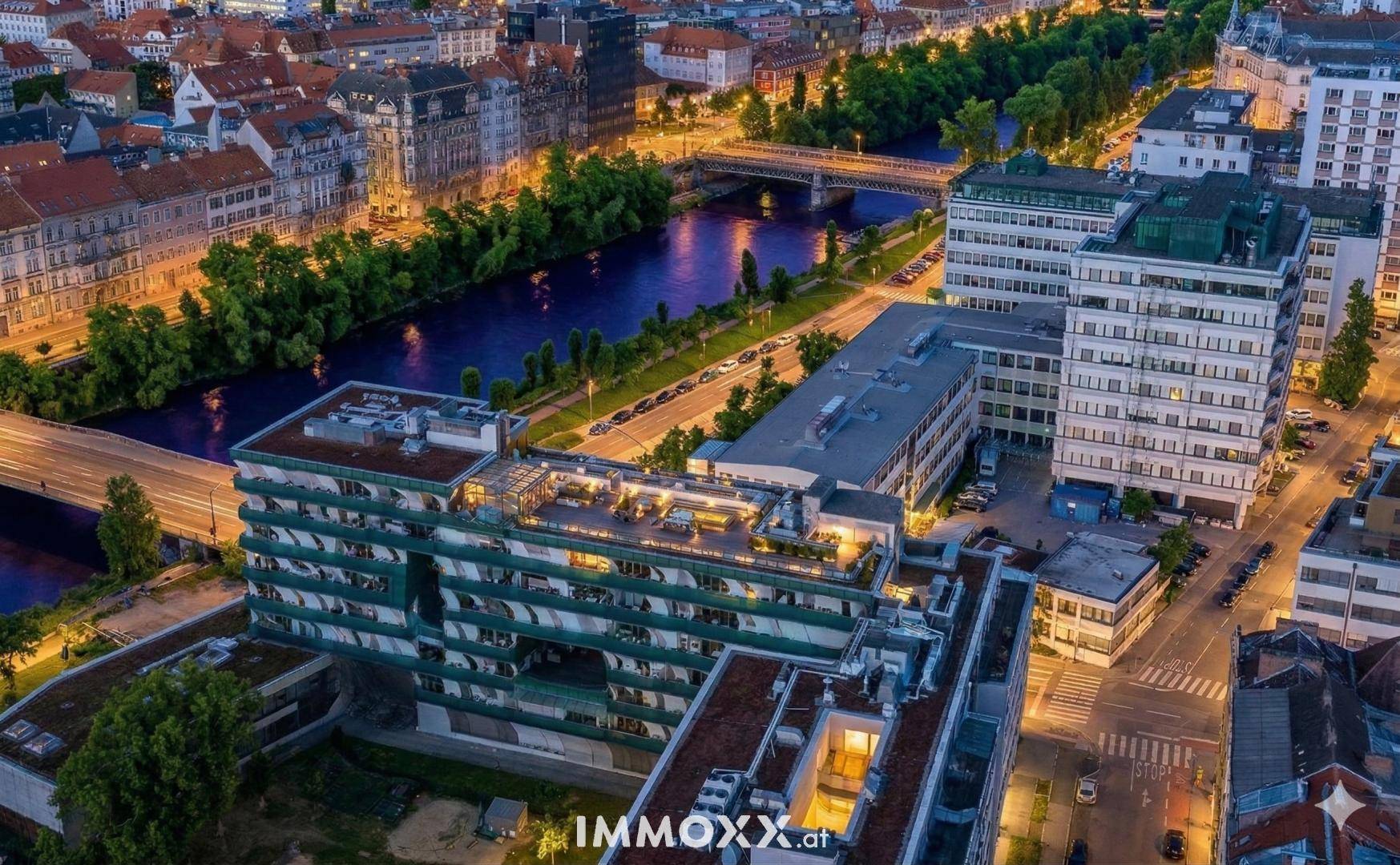 Nachtaufnahme der Stadt mit beleuchteten Gebäuden, Fluss und Brücken, die sich im Wasser spiegeln.