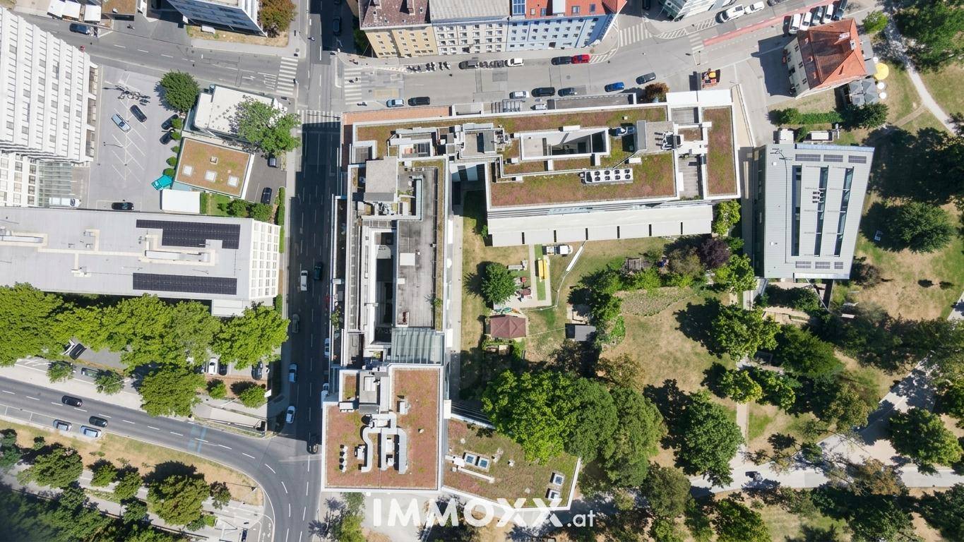 Luftaufnahme von Gebäuden mit begrünten Dächern, Straßen und umliegenden Grünflächen.