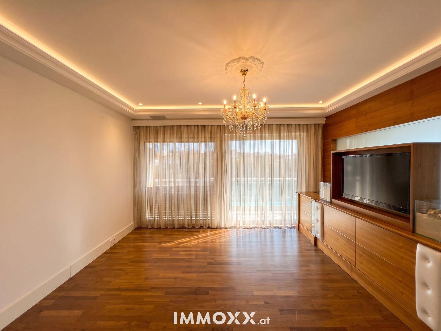 Geräumiger Wohnraum mit Holzfußboden, großen Fenstern und integriertem Medienschrank.