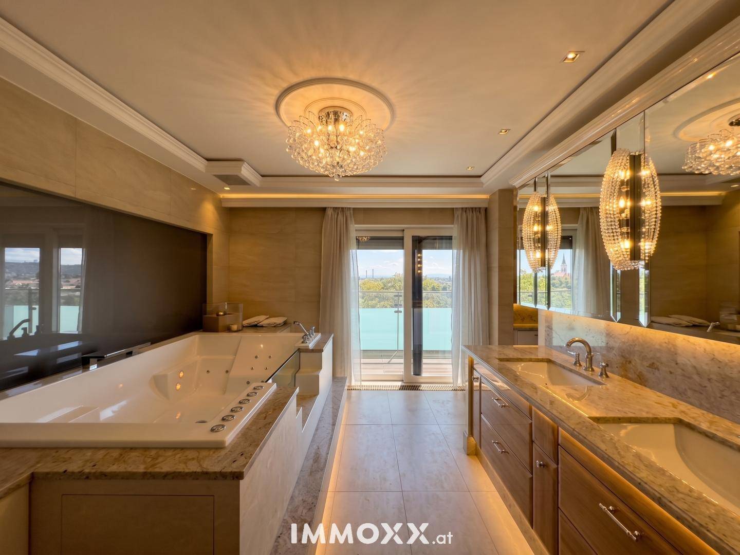 Luxuriöses Badezimmer mit großer Badewanne, Doppelwaschbecken und Balkonzugang.