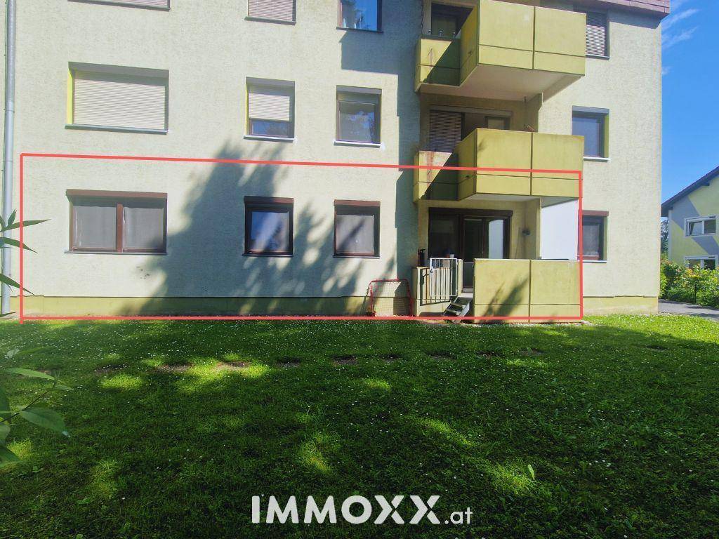 Außenansicht des Gebäudes mit einer Terrasse im Erdgeschoss und grünem Rasenbereich.