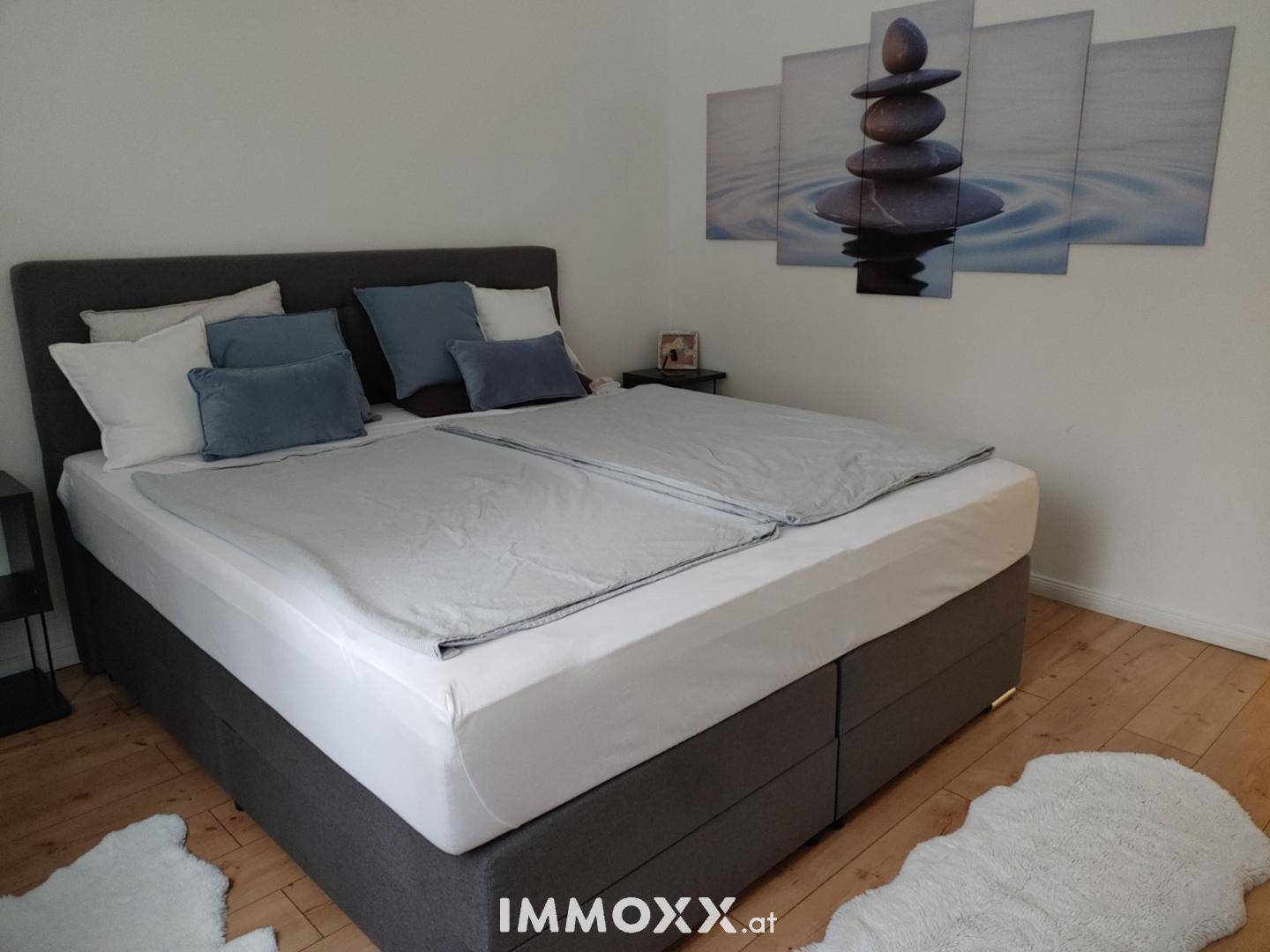 Gemütliches Schlafzimmer mit großem Doppelbett, Holzboden und beruhigender Wanddekoration.