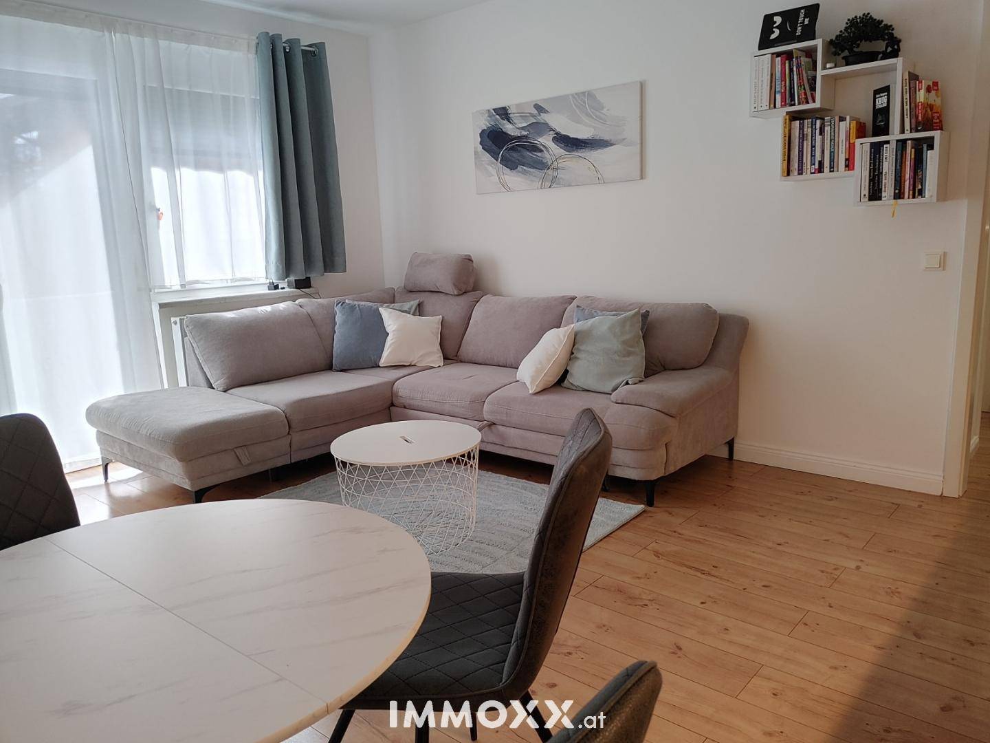 Heller Wohnbereich mit großem Ecksofa, Couchtisch und Essbereich, ausgestattet mit Holzboden.