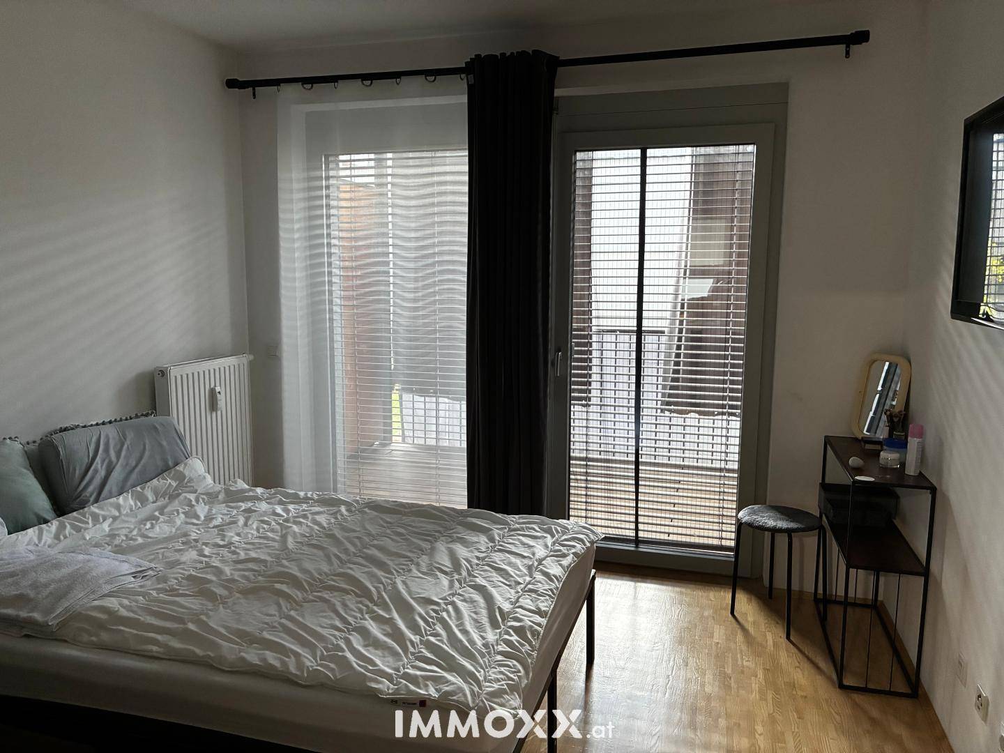 Schlafzimmer mit Doppelbett, Holzboden und Zugang zu einem Balkon.