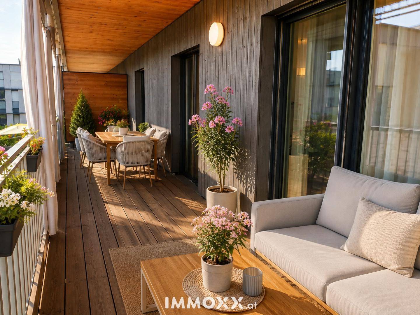Geräumiger Balkon mit Holzboden, Esstisch, Lounge-Möbeln und Pflanzen.