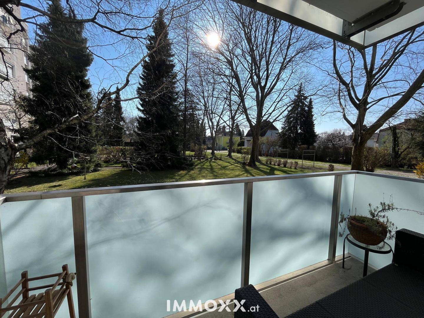 Sonniger Balkon mit Glasbrüstung und weitem Blick ins Grüne.
