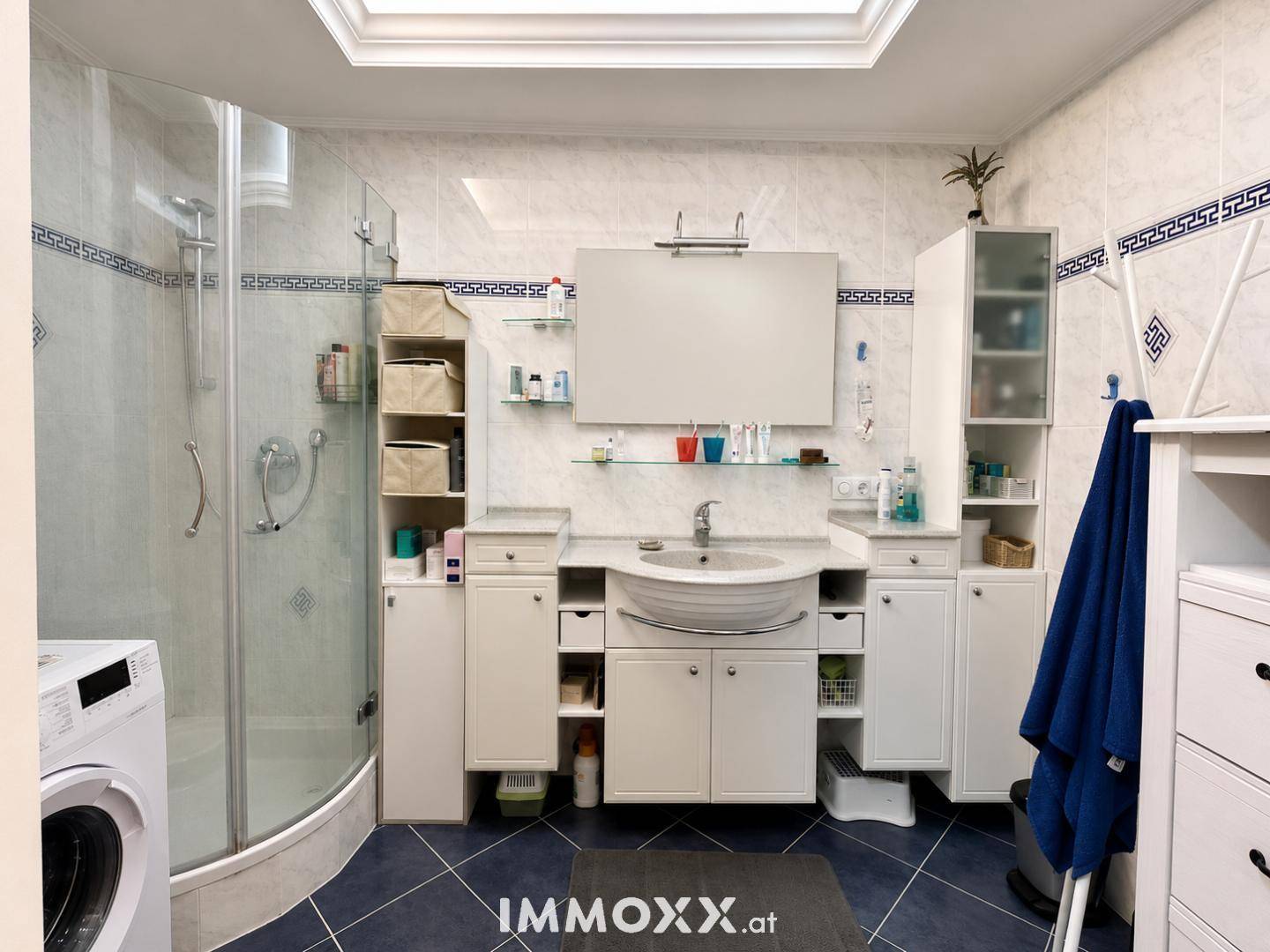 Badezimmer mit Dusche, Waschbecken, Spiegelschrank und Dachfenster für Tageslicht.