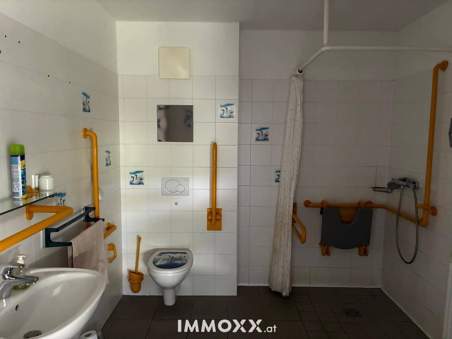 Barrierefreies Badezimmer mit Haltegriffen, ebenerdiger Dusche und wandhängendem WC.