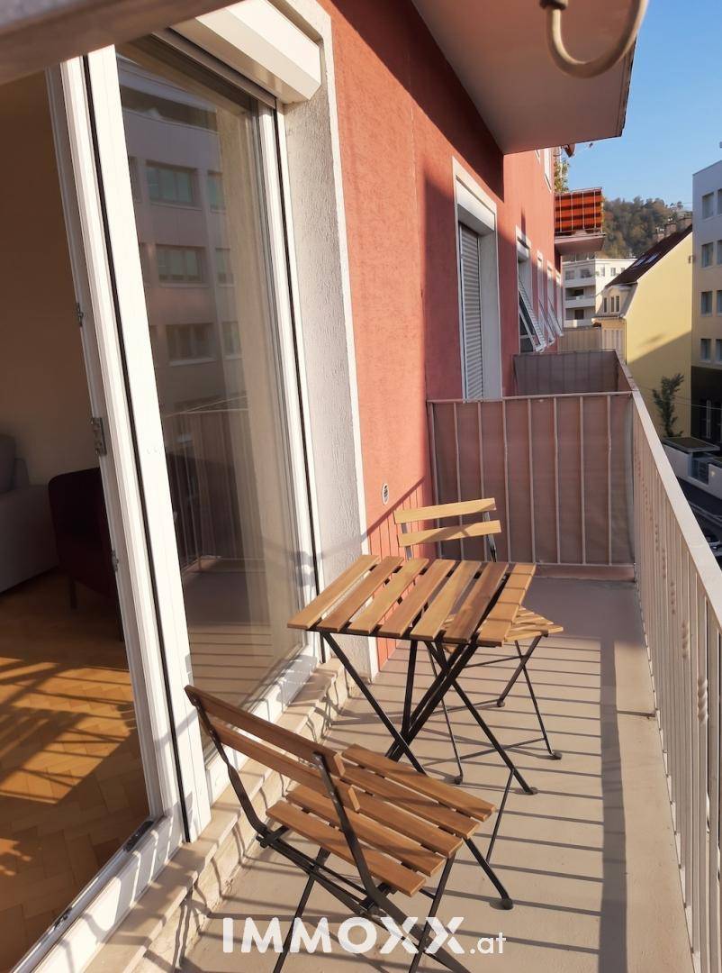 Sonniger Balkon mit Holztisch und Stühlen, ideal für entspannte Stunden im Freien.