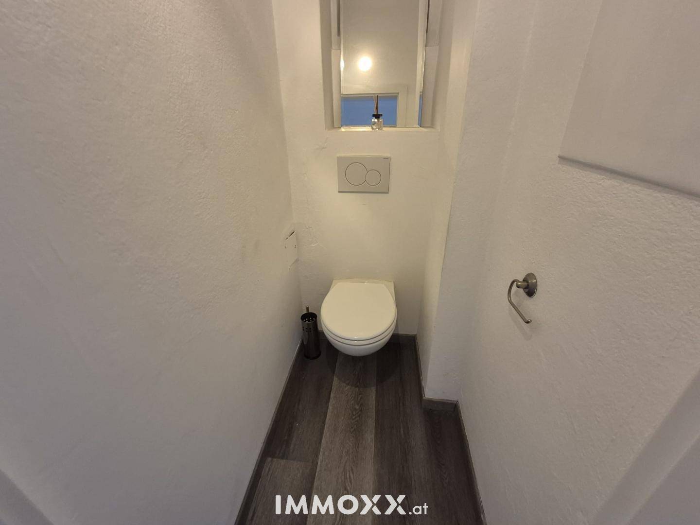 Separates WC mit wandhängender Toilette und kleinem Spiegel, funktional und platzsparend.