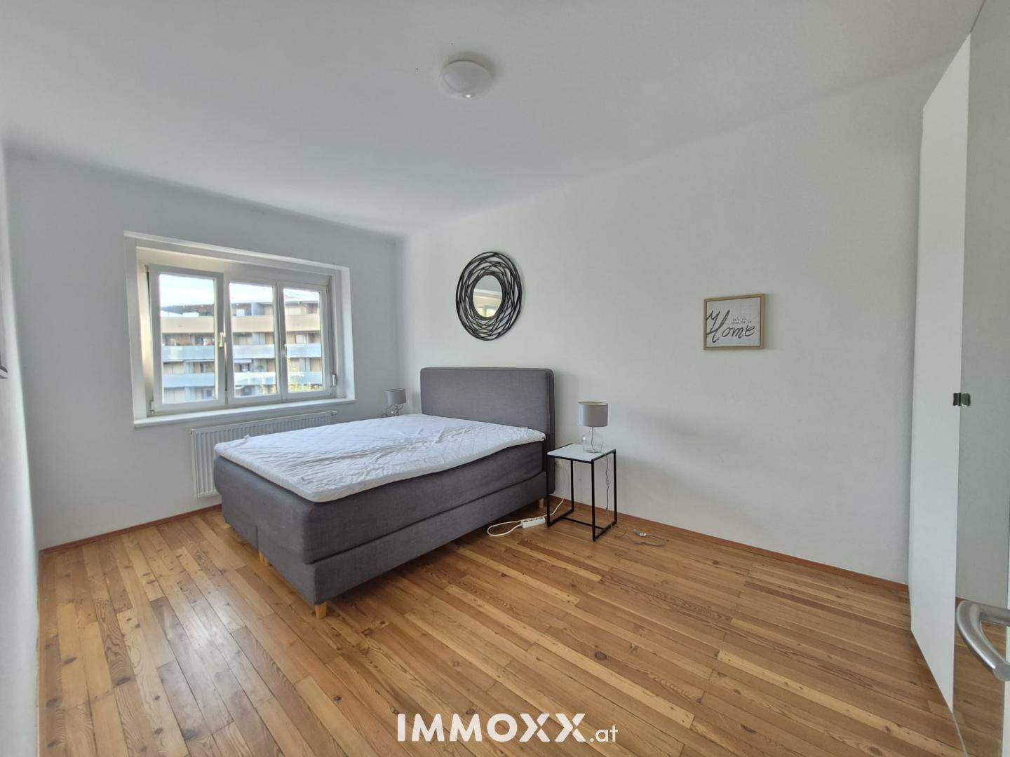 Gemütliches Schlafzimmer mit Holzdielenboden und großem Fenster, bietet eine ruhige Atmosphäre.