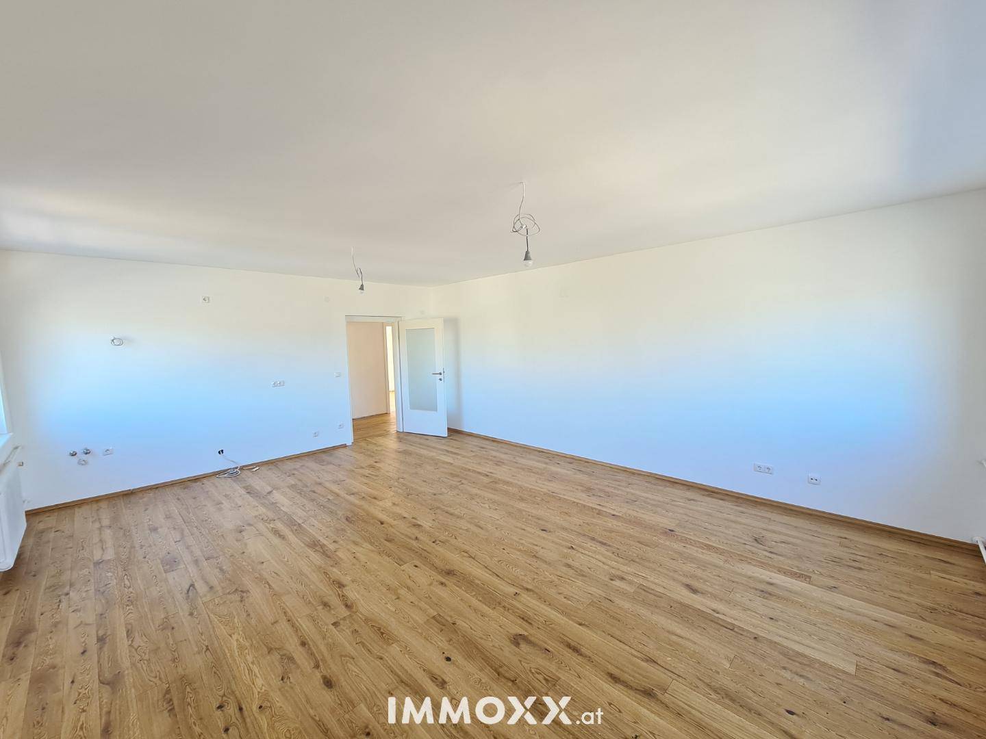 Geräumiges, leeres Zimmer mit Holzboden und weißen Wänden, bereit zur individuellen Gestaltung.