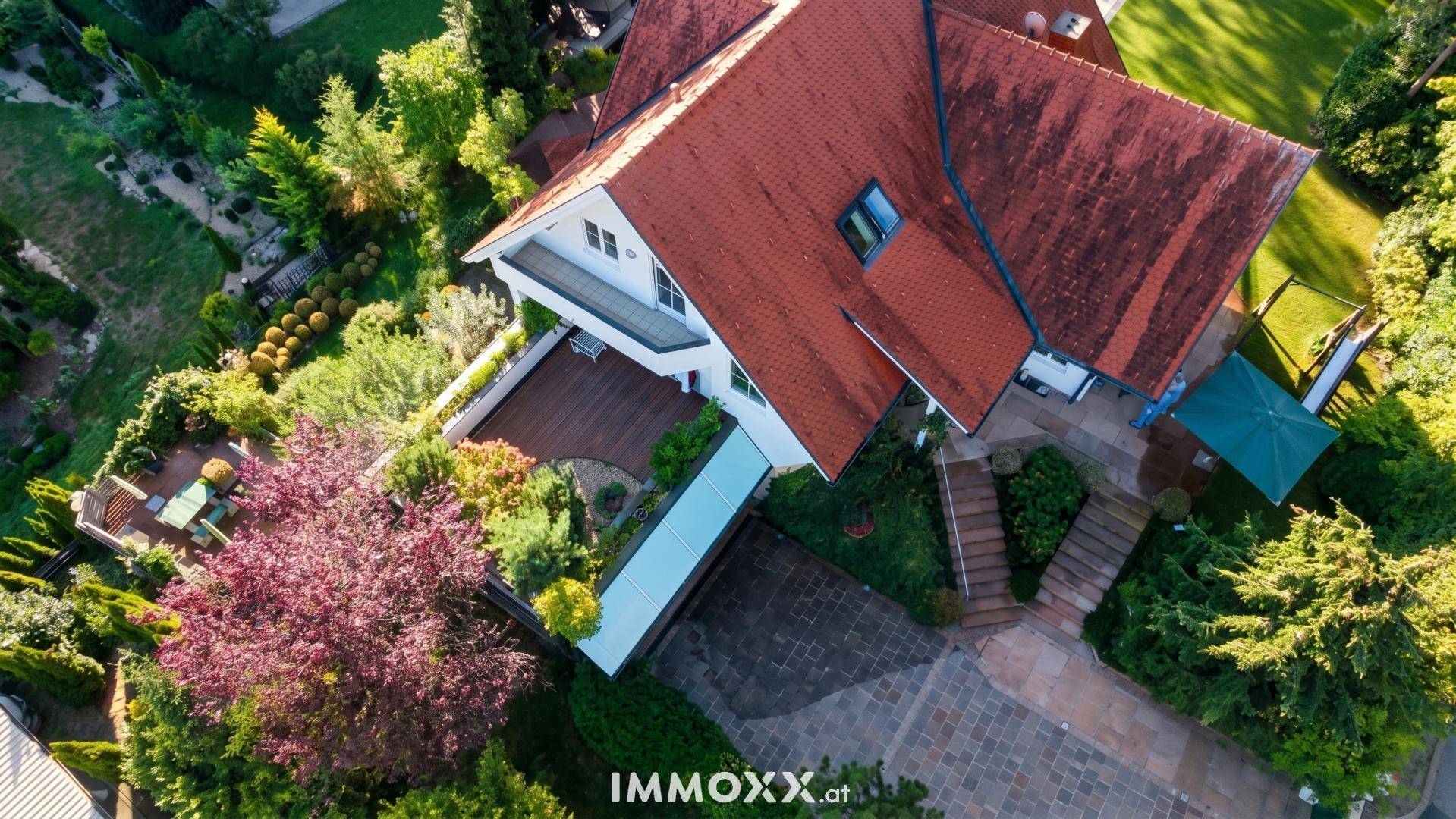 Luftaufnahme des Anwesens mit Haus, Zufahrt, Garten und der umliegenden grünen Landschaft.
