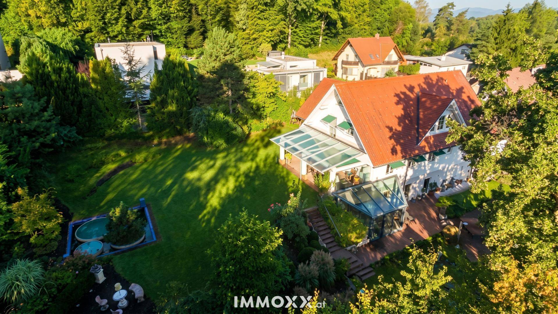 Luftaufnahme des Hauses mit weitläufigem Garten, Whirlpoolbereich und üppiger Vegetation.
