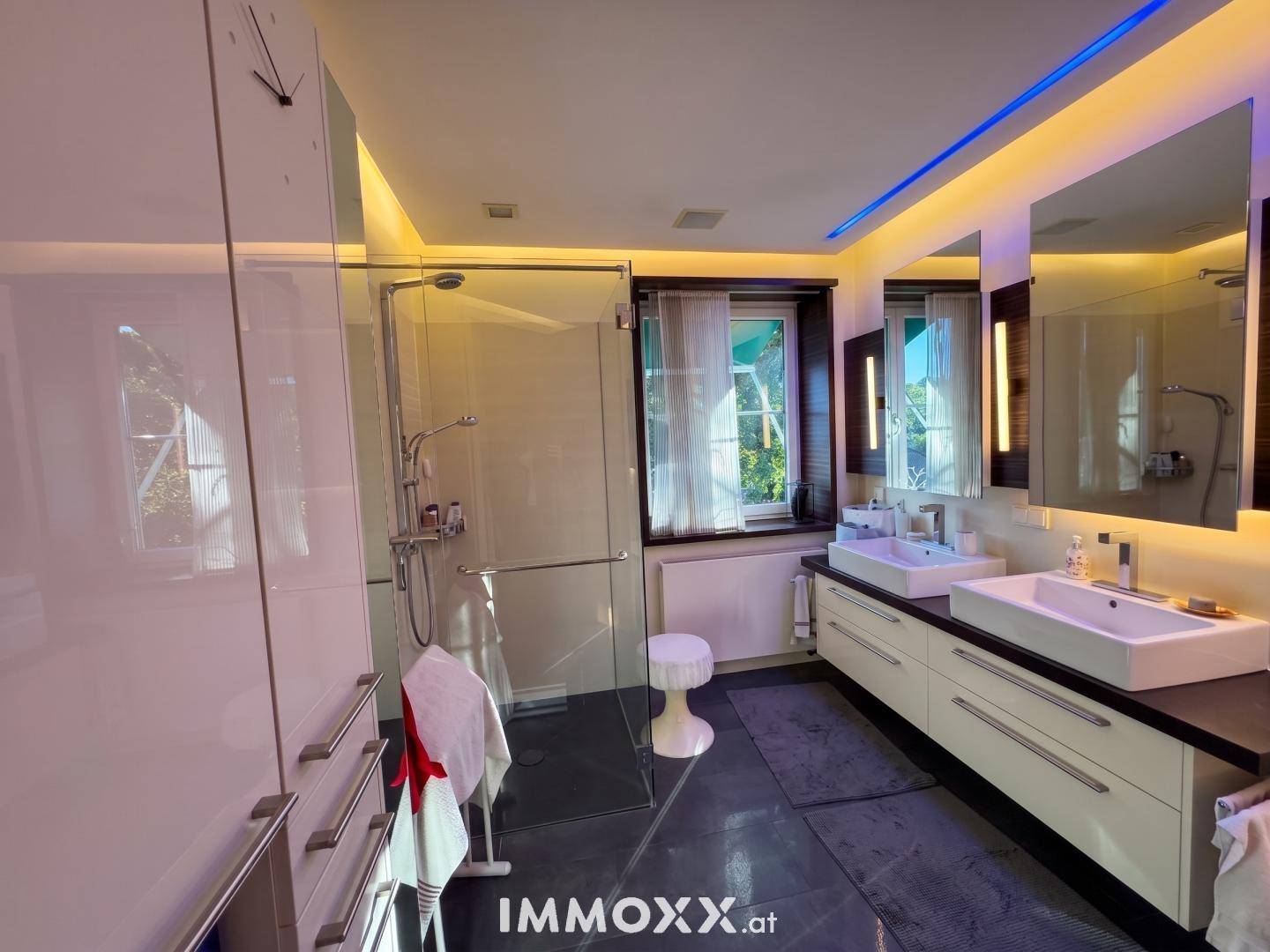 Modernes Badezimmer mit begehbarer Dusche, Doppelwaschbecken und großen Spiegeln.