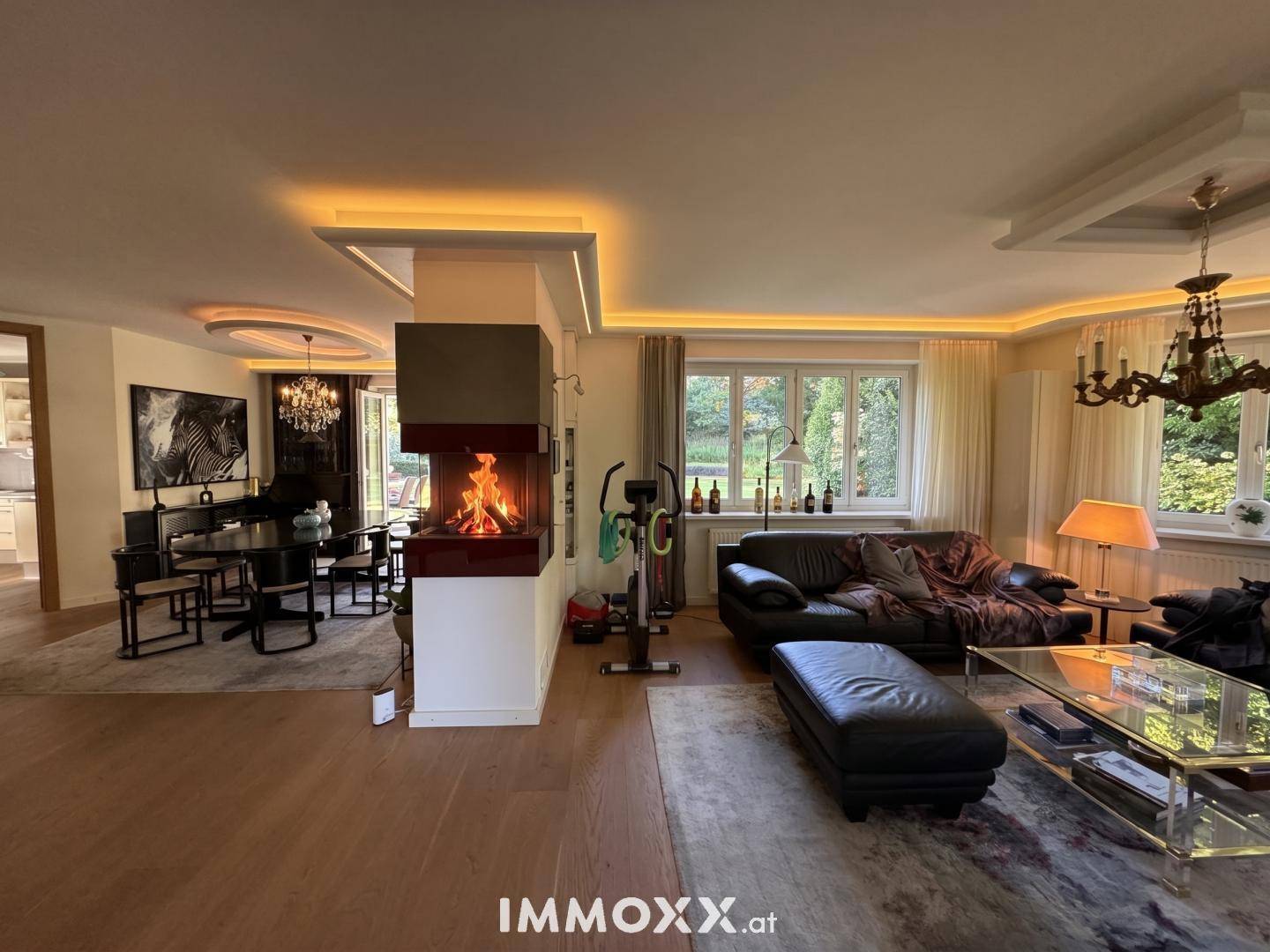 Offener Wohn- und Essbereich mit modernem Kamin, Holzfußboden und Blick in den Garten.