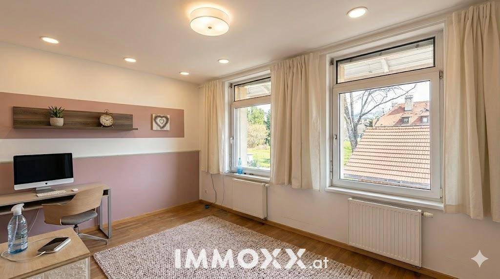 Helles Zimmer mit Holzfußboden, zwei Fenstern und einem Schreibtisch, ideal als Schlaf- oder Arbeitszimmer.
