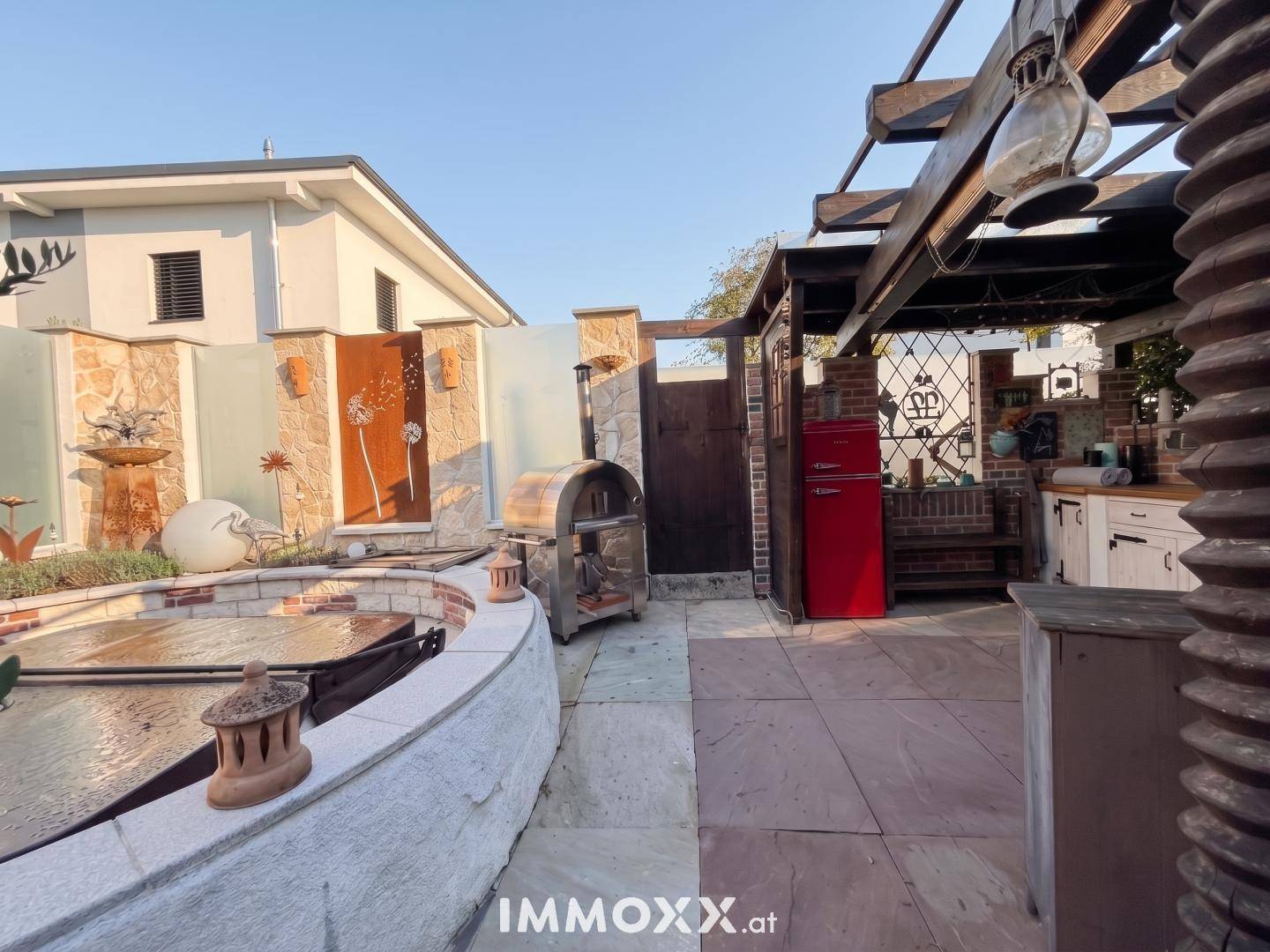 Entspannender Außenbereich mit Whirlpool, Outdoor-Pizzaofen und dekorativen Wandelementen.