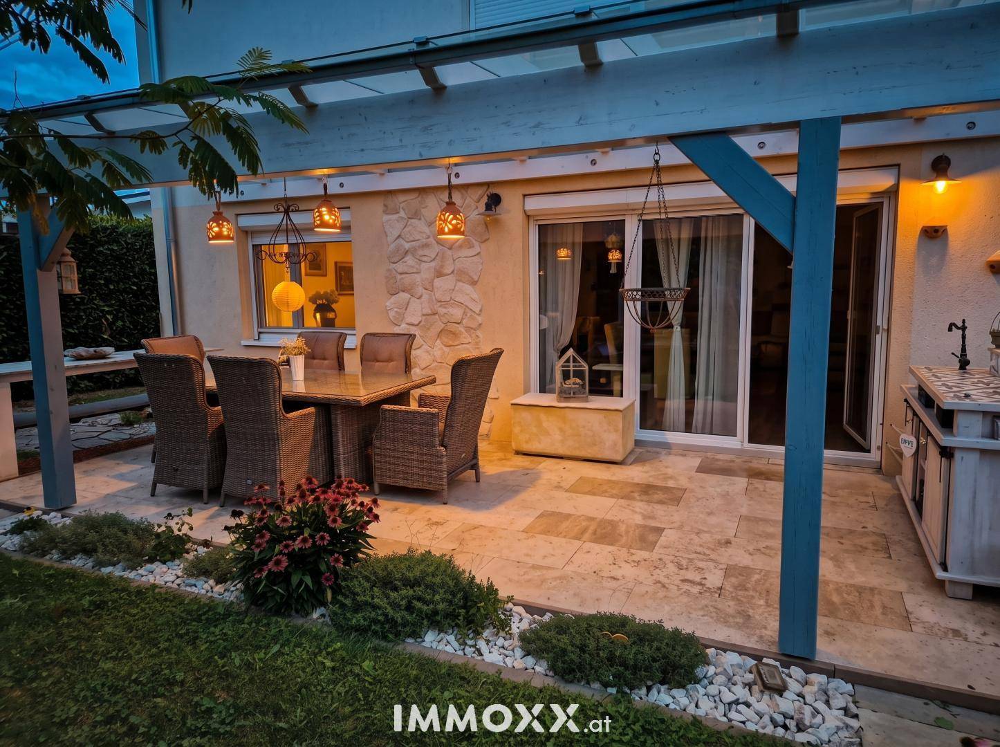 Gemütliche Terrasse mit Esstisch unter einer Pergola und Zugang zum Haus, ideal für Abendessen im Freien.