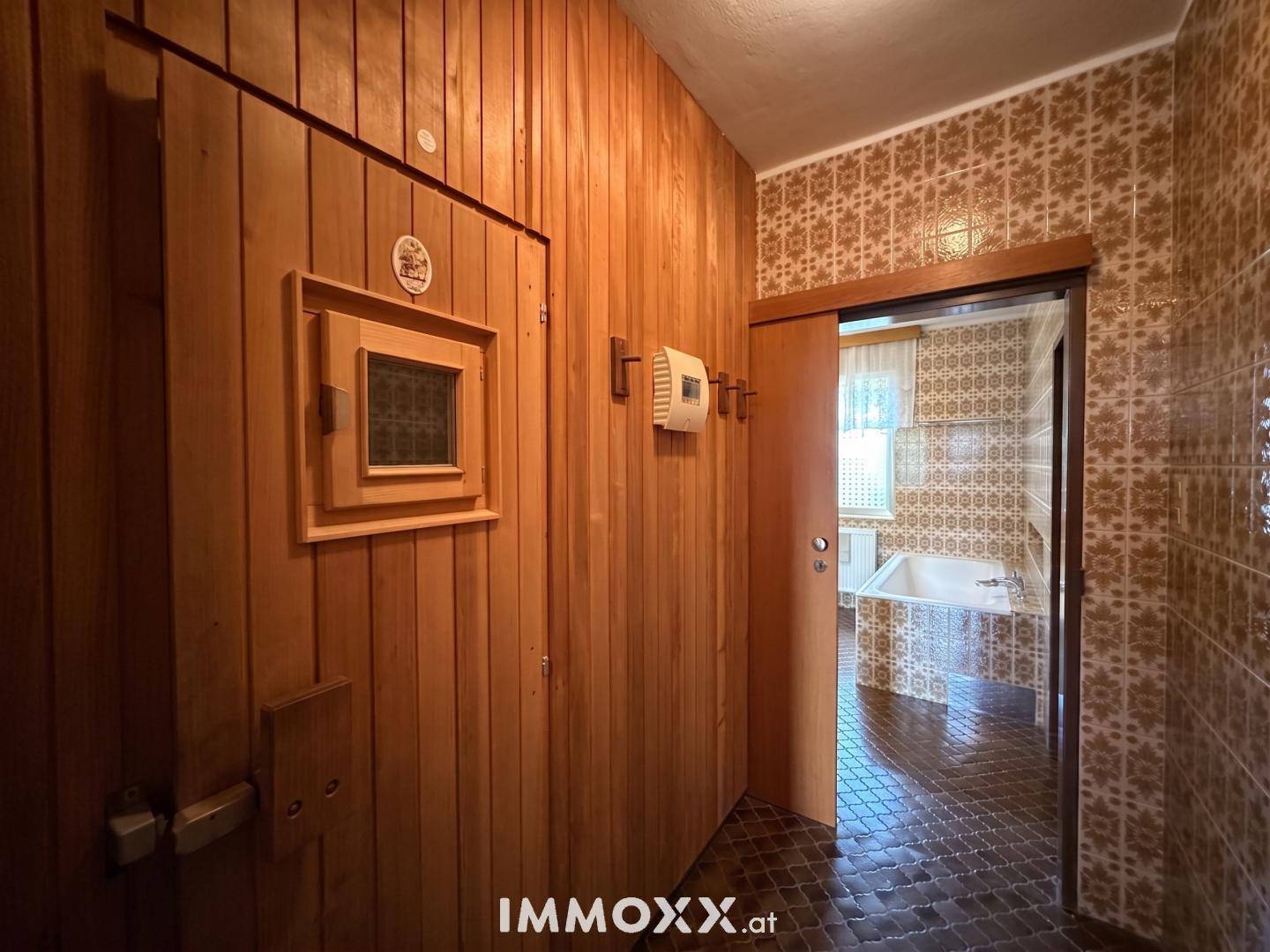 Flur mit Holzwänden, der zu einer Sauna führt, und einem Blick ins Badezimmer.