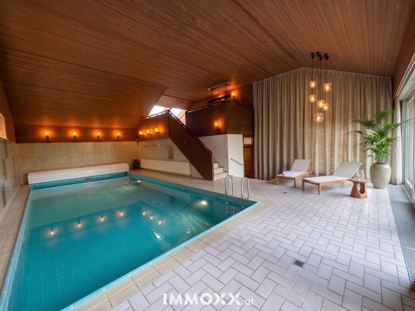 Innenpoolbereich mit Holzdecke, gefliestem Boden und Liegestühlen für Entspannung.