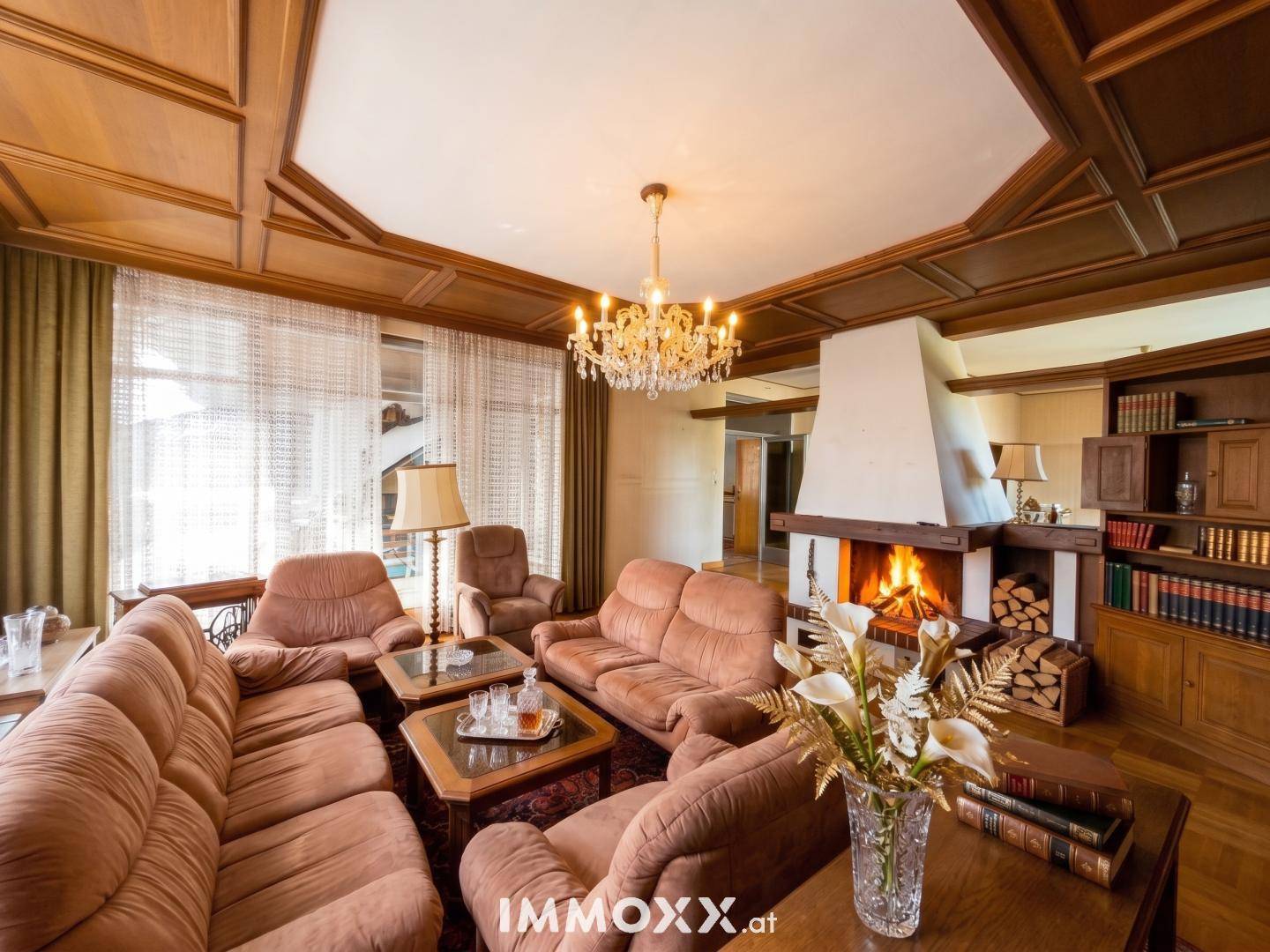 Geräumiges Wohnzimmer mit großem Kamin, Holzkassettendecke und bequemen Sofas.