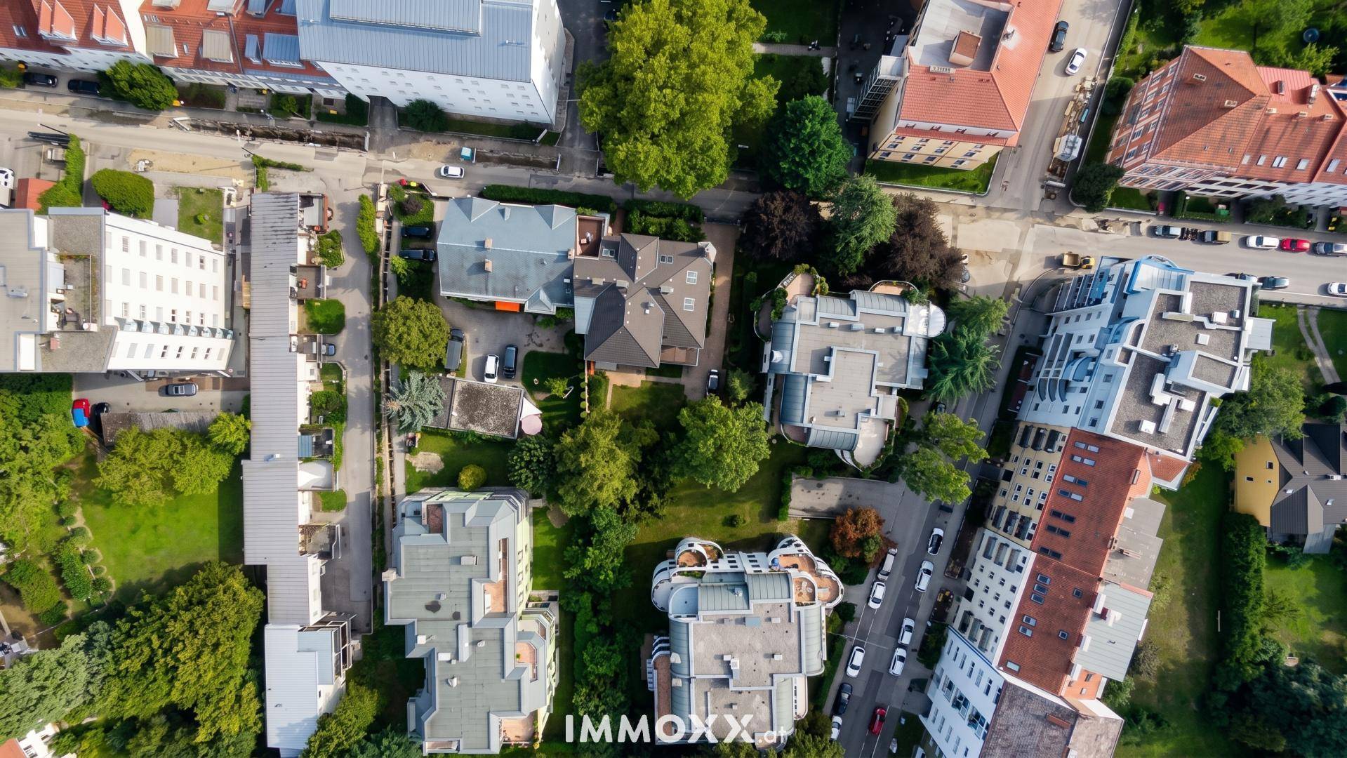 Vertikale Luftaufnahme einer städtischen Wohngegend mit Gebäuden, Straßen und viel Grün.