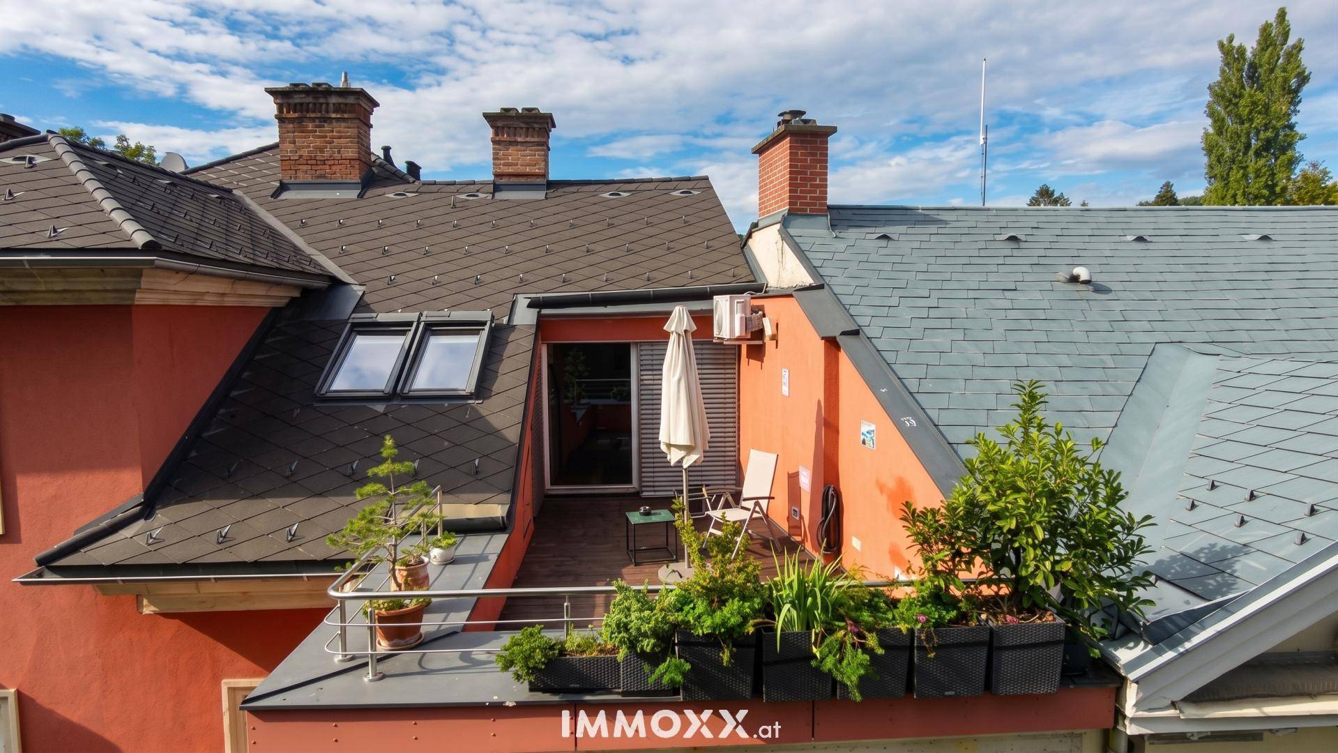 Gemütliche Dachterrasse mit Sitzgelegenheiten, Pflanzen und Blick auf die Dächer der Umgebung.