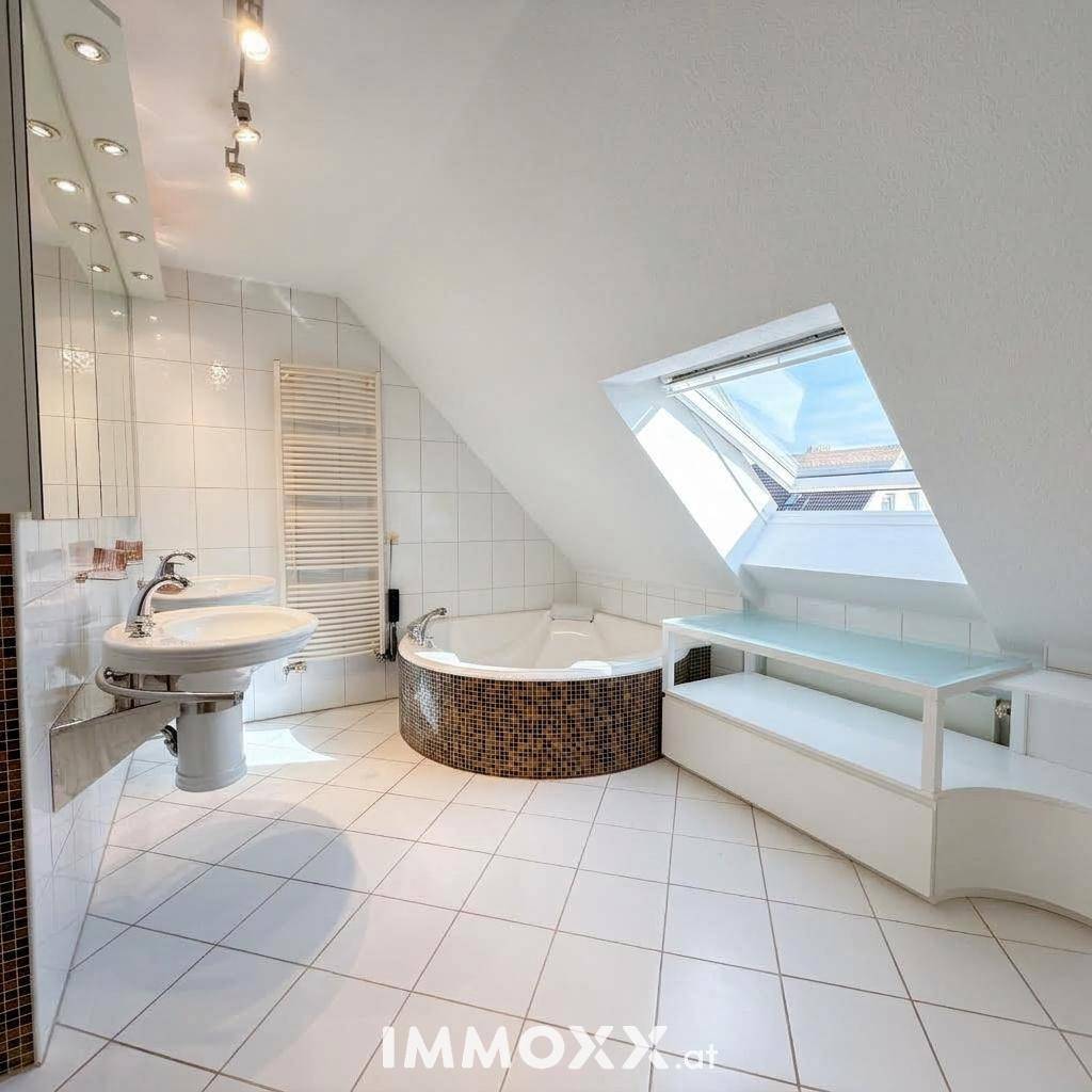 Helles Badezimmer im Dachgeschoss mit Eckbadewanne, Dachfenster und weißen Fliesen.