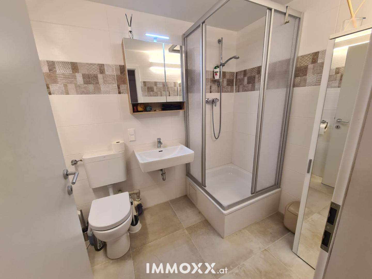 Funktionales Badezimmer mit Dusche, Waschbecken und WC, ausgestattet mit Fliesen.