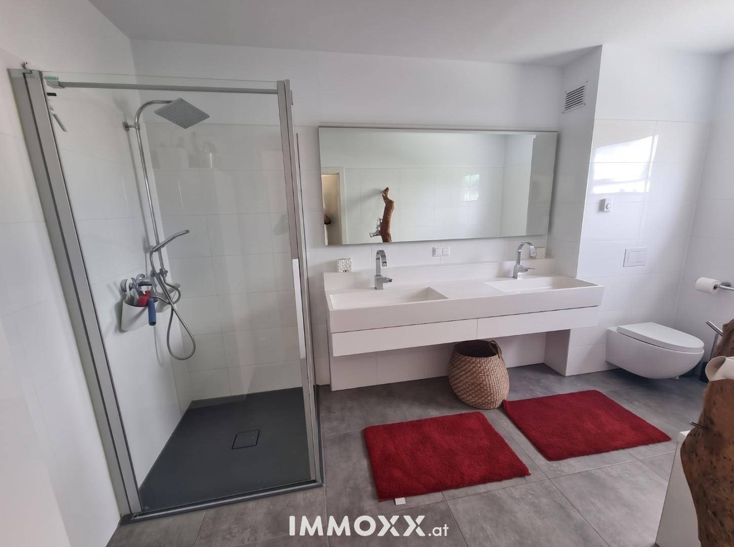 Geräumiges Badezimmer mit begehbarer Dusche, Doppelwaschbecken und Wand-WC.