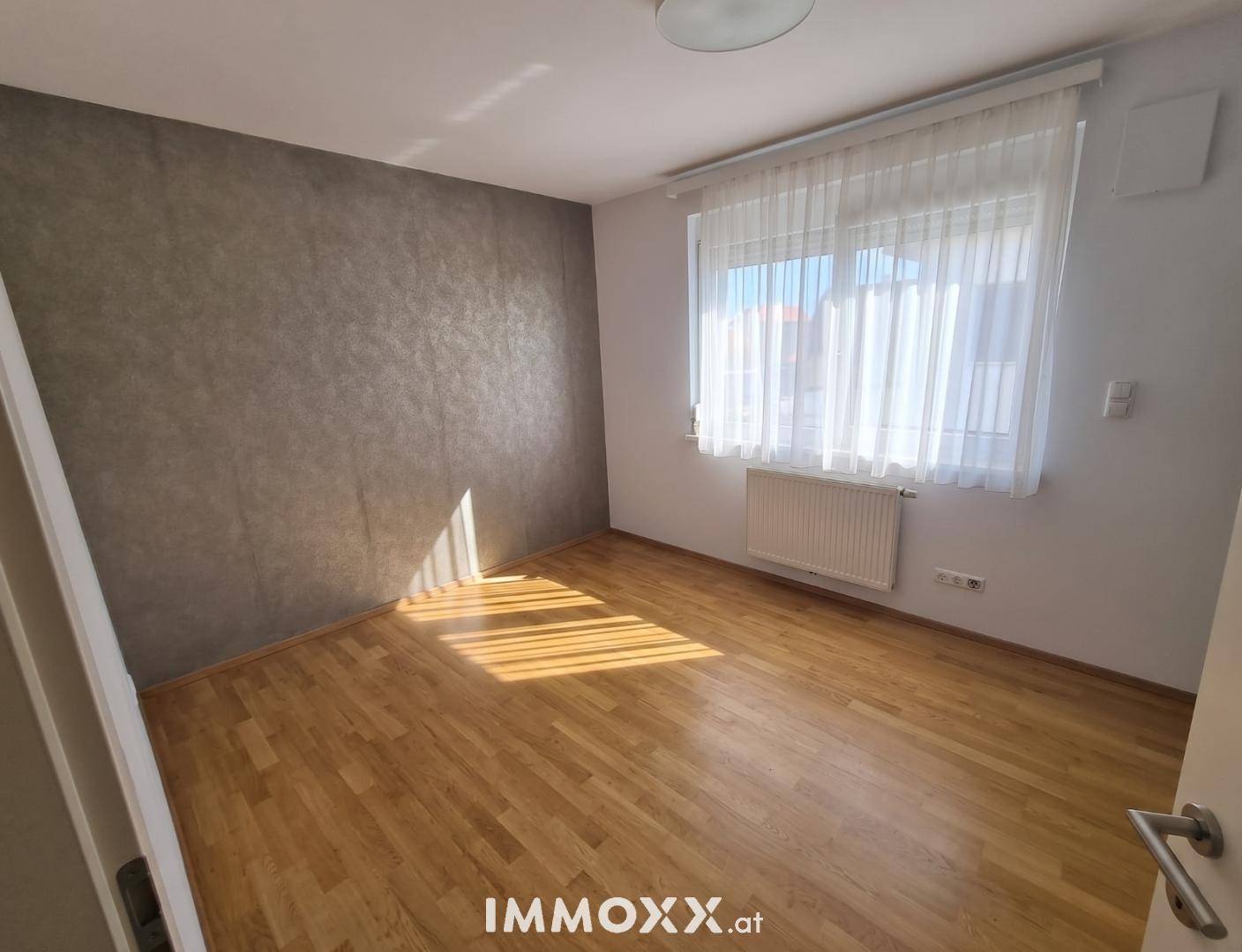 Helles Zimmer mit Holzboden und strukturierten Wänden, ideal als Schlaf- oder Gästezimmer.
