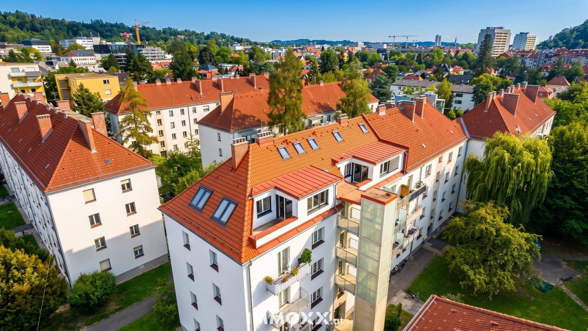 Luftaufnahme eines Wohngebäudes mit roten Dächern und einem modernen externen Glasaufzug.