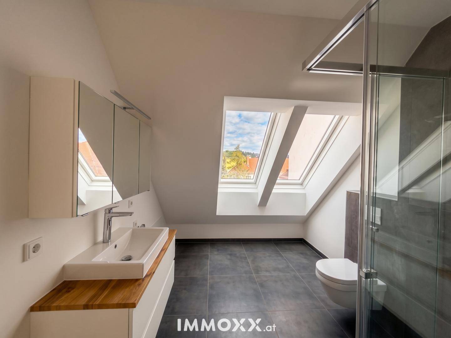 Modernes Badezimmer mit begehbarer Dusche, Einzelwaschbecken und Dachfenstern.