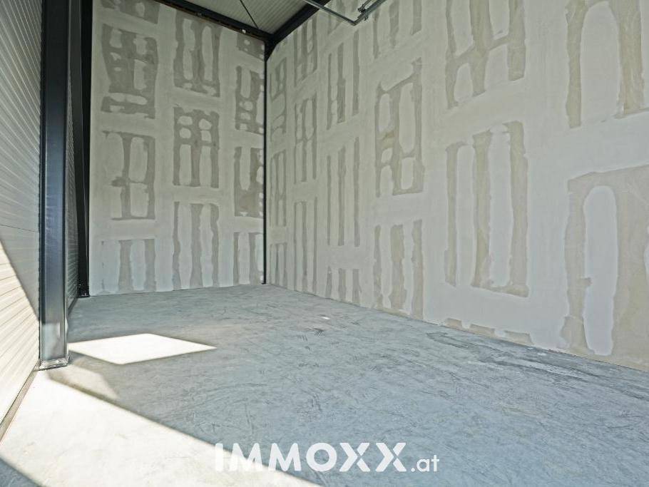 Innenansicht einer Gewerbeeinheit mit Betonboden und unfertigen Wänden, die auf Ausbau warten.