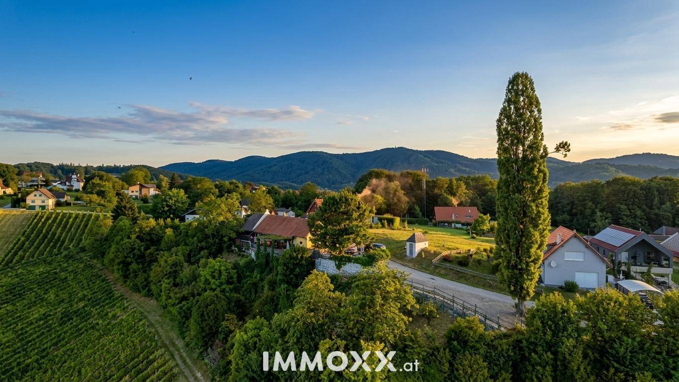 Malerische Luftaufnahme einer ländlichen Siedlung umgeben von Weinbergen und grünen Hügeln bei Sonnenuntergang.