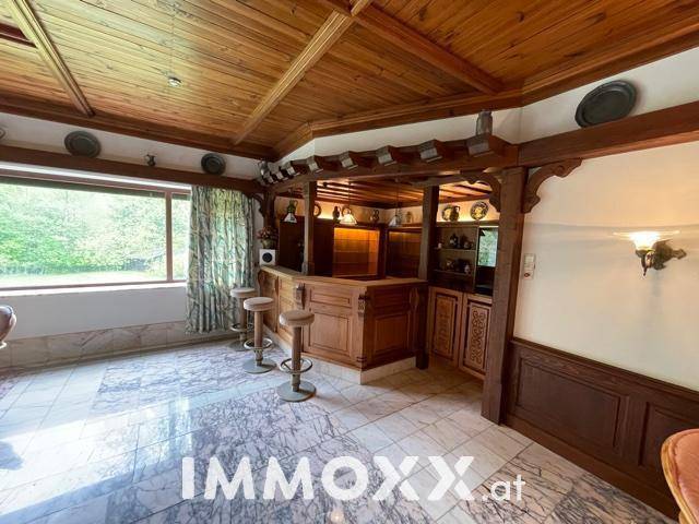 Gemütliche Bar im Innenpoolbereich mit Holzvertäfelung und Hockern.