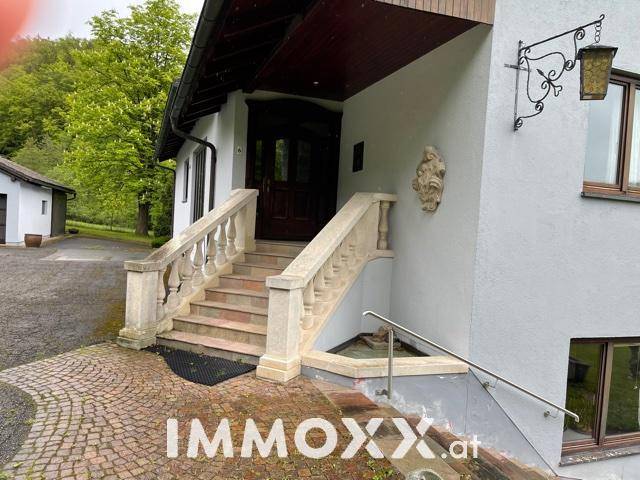 Hauseingang mit steinerner Balustrade, Treppe und dekorativer Wandleuchte.
