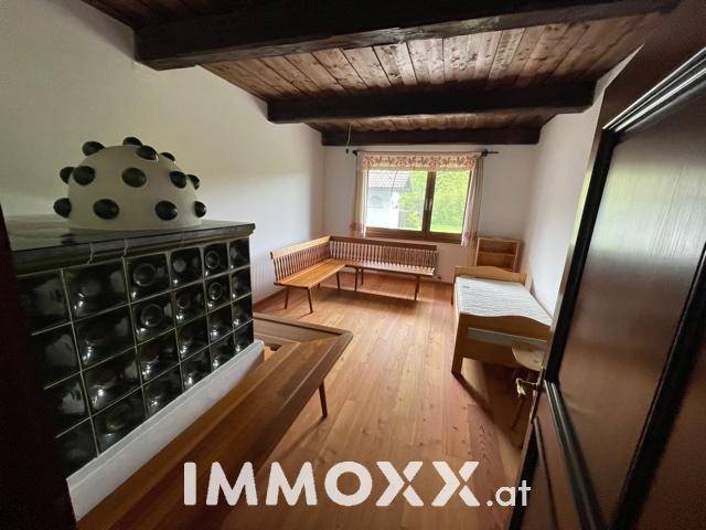 Rustikales Schlafzimmer mit Holzbalkendecke, Kachelofen und Holzboden.