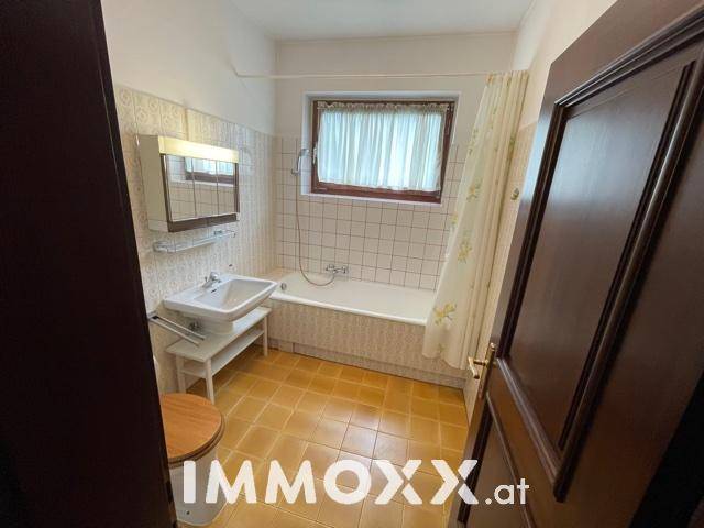 Badezimmer mit gelben Fliesen, Badewanne und Fenster für Tageslicht.